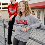 Two people wearing Biola University sweatshirts standing near a chain-link fence.
