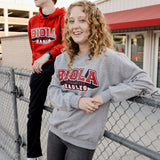 Two people wearing Biola University sweatshirts standing near a chain-link fence.